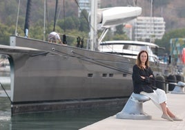 Sasha Romashova, sitting next to a large sailing yacht at the megayacht marina in Malaga.